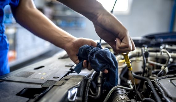 Photo of male mechanic measuring the oil level of an engine at an auto shop. Mechanic checking oil level in a car service garage. Repairing engine at service station. Car repair.
.  (Photo of male mechanic measuring the oil level of an engine at an a